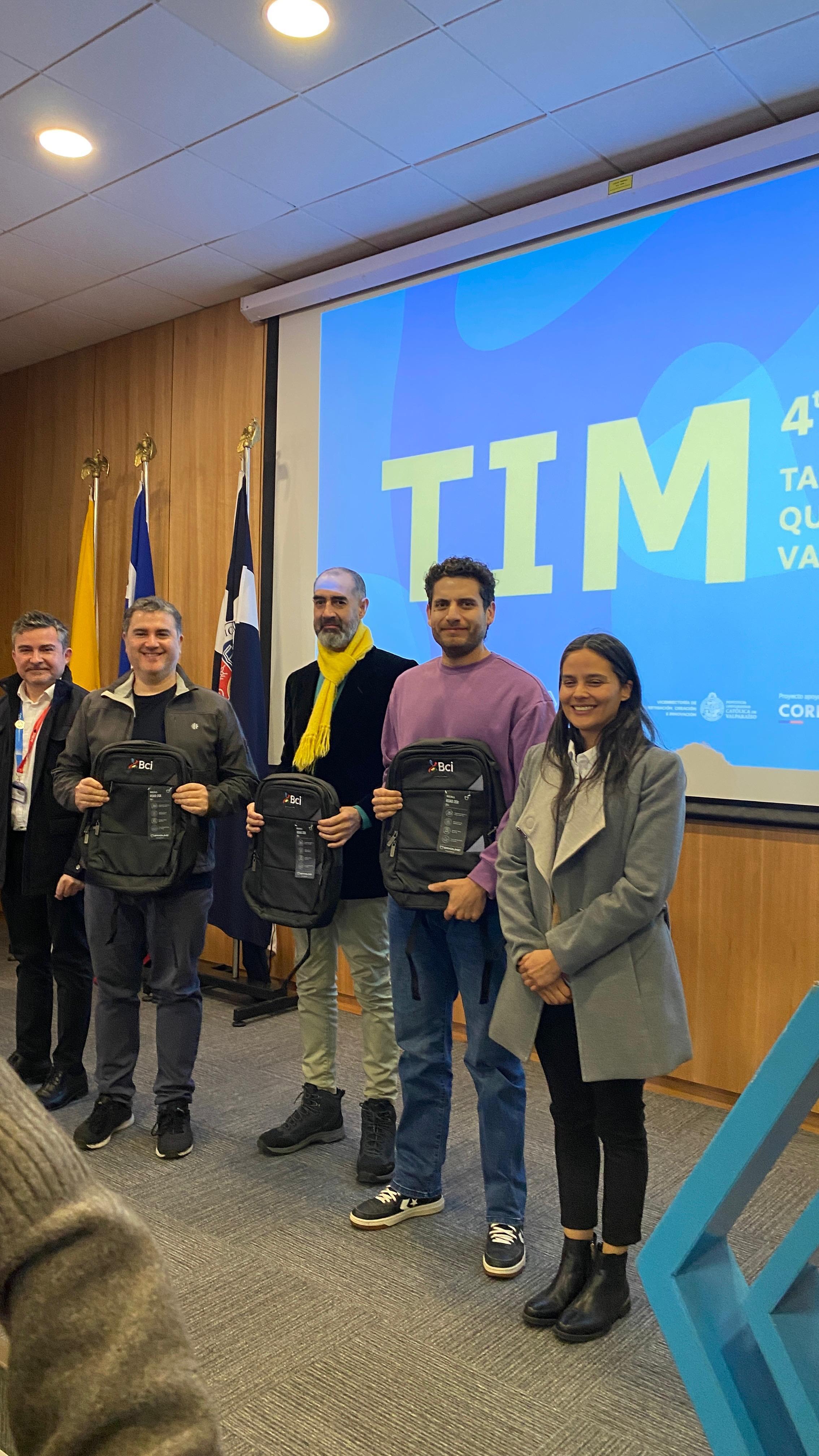 Equipo recibiendo mochilas de premiación en el evento TIM