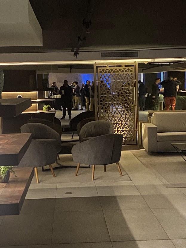Sala de estar de un evento corporativo con asistentes conversando al fondo